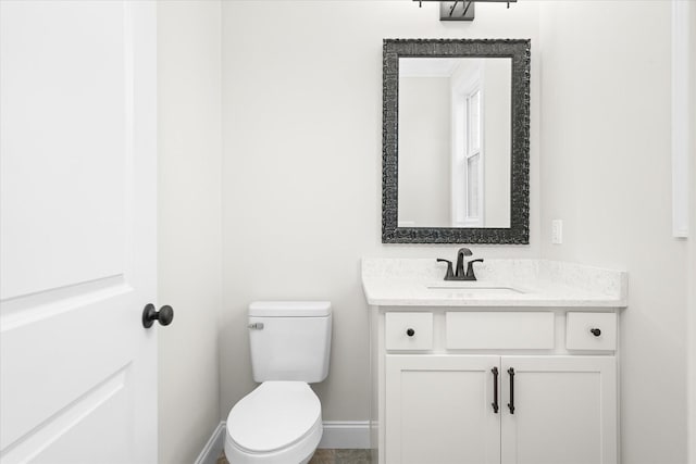 bathroom featuring toilet, baseboards, and vanity