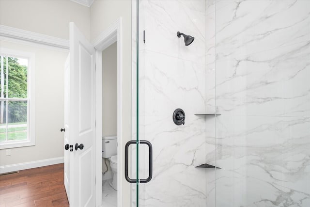 bathroom featuring baseboards, toilet, visible vents, wood finished floors, and a marble finish shower