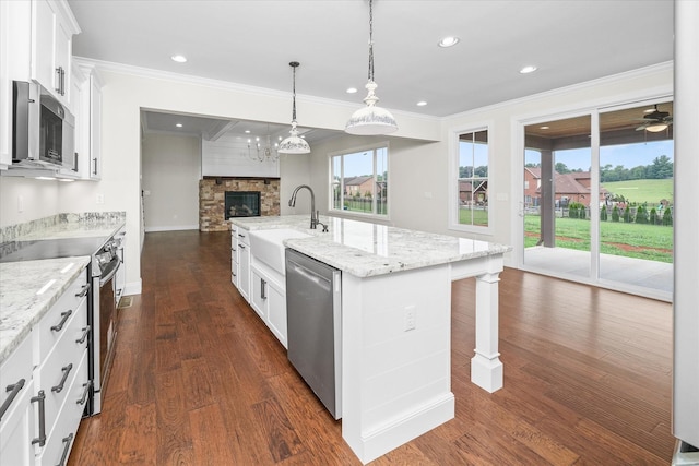 kitchen featuring a sink, open floor plan, crown molding, stainless steel appliances, and a kitchen island with sink