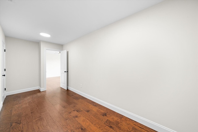 spare room with dark wood-style flooring and baseboards