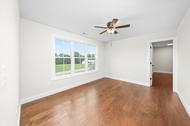 spare room featuring dark wood-style flooring, baseboards, a ceiling fan, and visible vents