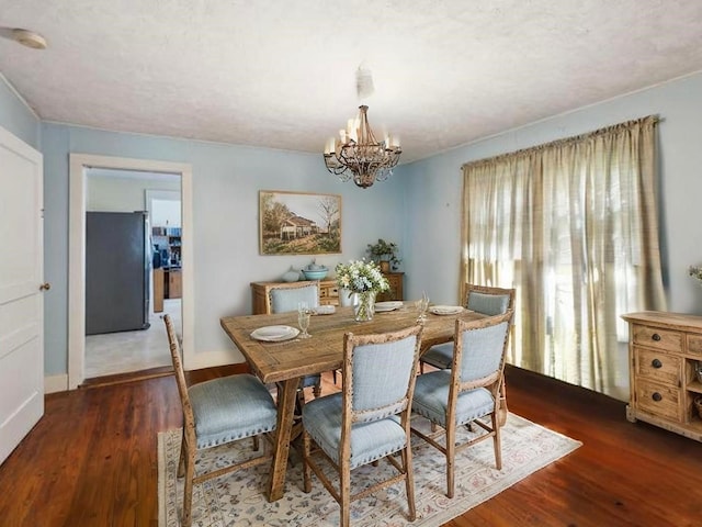dining room with a chandelier, wood finished floors, and baseboards