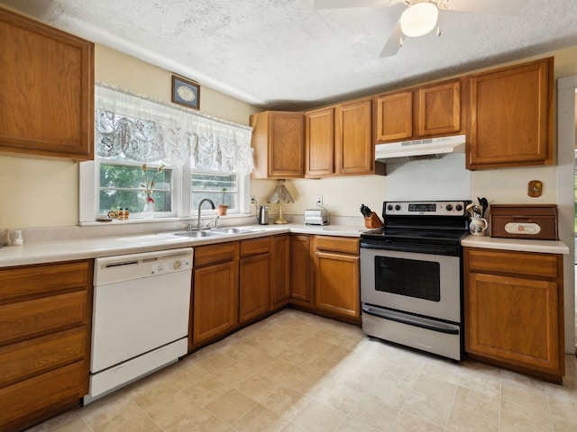 kitchen with white dishwasher, under cabinet range hood, brown cabinetry, stainless steel electric range oven, and a sink