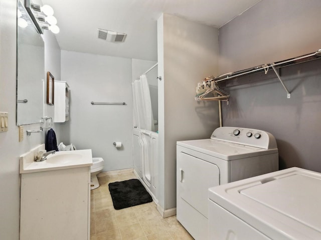 clothes washing area featuring washer and clothes dryer, a sink, laundry area, visible vents, and light tile patterned floors