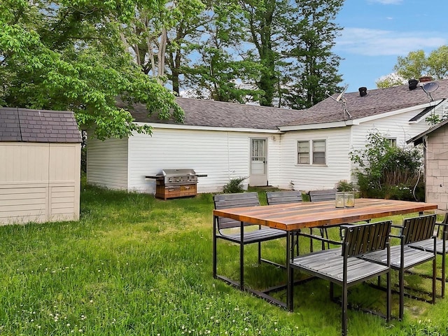 back of property featuring a lawn, an outbuilding, outdoor dining space, and a storage shed
