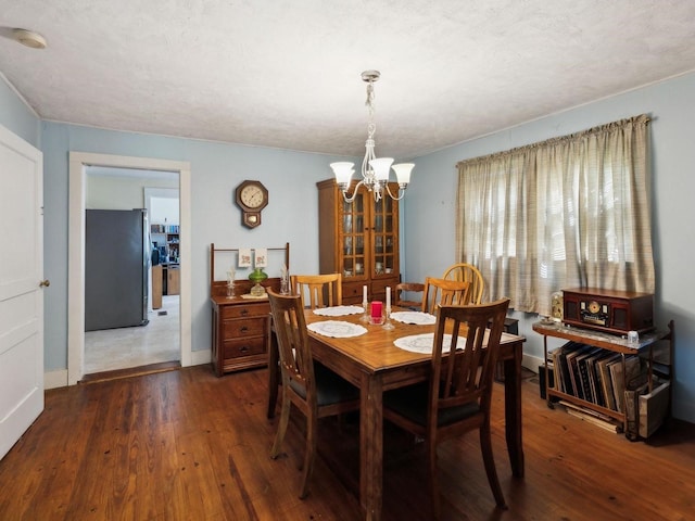 dining room with wood finished floors, baseboards, and a notable chandelier