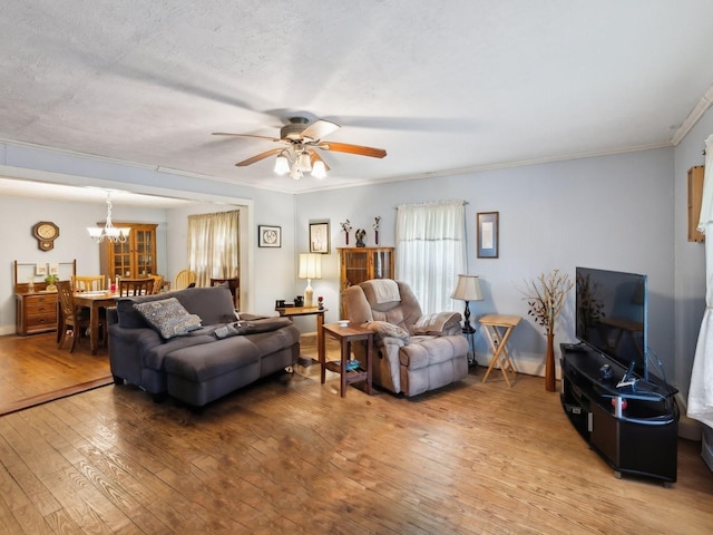 living area with crown molding, light wood-style floors, and ceiling fan with notable chandelier