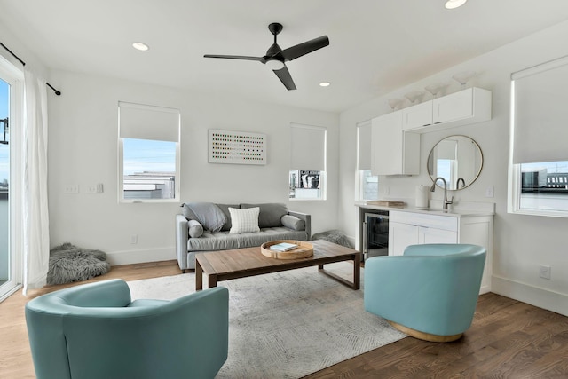 living room featuring a wealth of natural light, wood finished floors, ceiling fan, and wine cooler