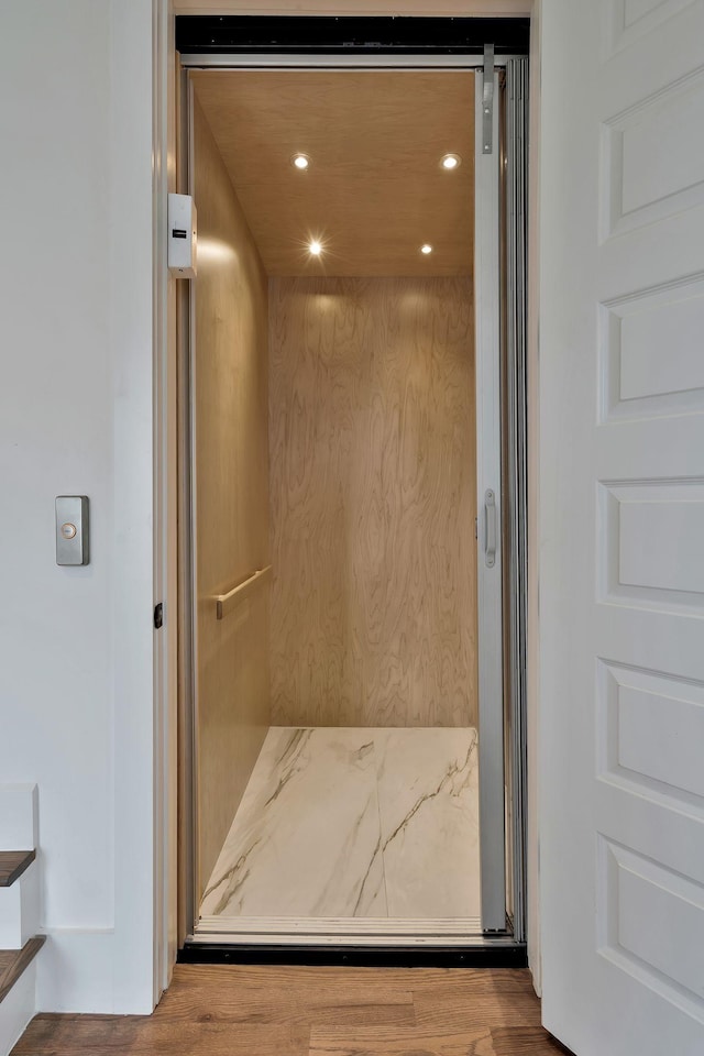 bathroom featuring wood finished floors, elevator, and recessed lighting