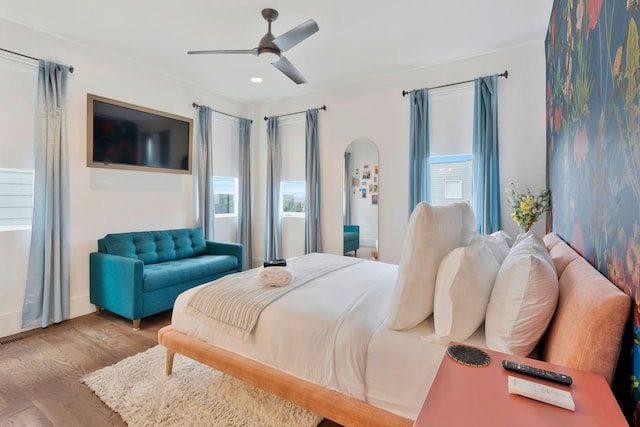 bedroom featuring wood finished floors, recessed lighting, arched walkways, a ceiling fan, and baseboards