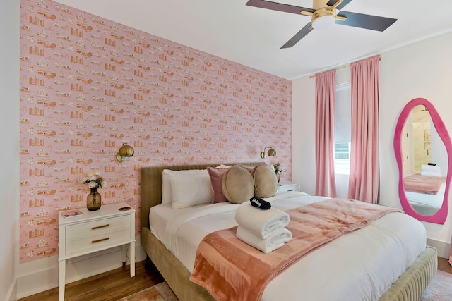 bedroom with baseboards, ceiling fan, wallpapered walls, and wood finished floors
