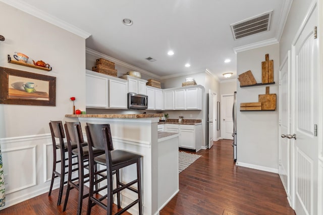 5002 Fox Run S, Spring Hill, TN 37174 - kitchen with visible vents, stainless steel microwave, a kitchen bar, and ornamental molding