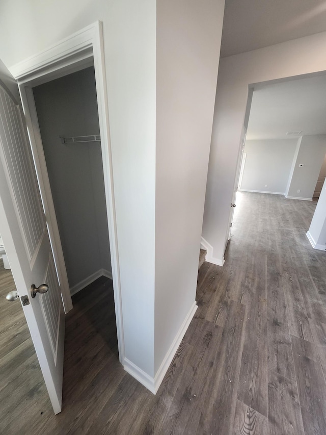 hallway featuring an upstairs landing, dark wood-type flooring, and baseboards