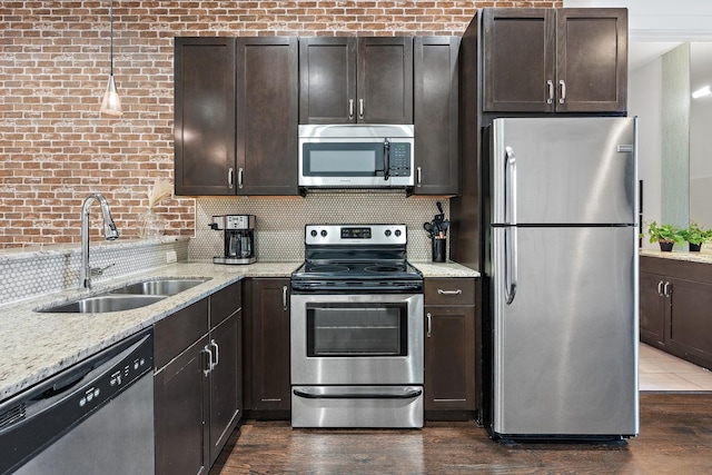 kitchen featuring dark brown cabinets, decorative backsplash, appliances with stainless steel finishes, and a sink