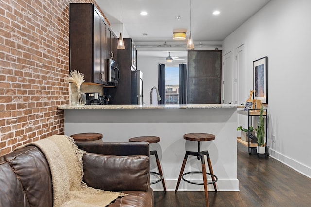 kitchen with a peninsula, dark brown cabinetry, dark wood-style flooring, baseboards, and appliances with stainless steel finishes