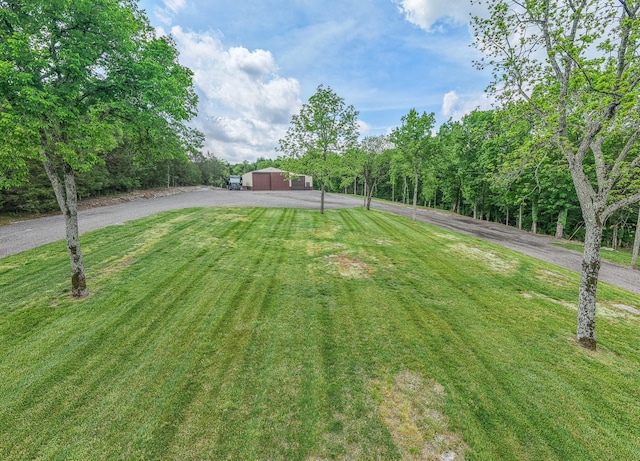 view of yard with an outdoor structure, a pole building, and aphalt driveway