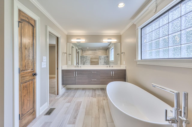 full bath with a sink, visible vents, crown molding, double vanity, and a freestanding tub