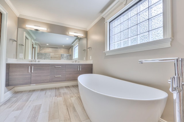 bathroom with double vanity, crown molding, a soaking tub, and wood finished floors