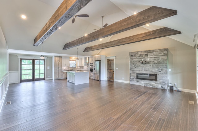 unfurnished living room with a ceiling fan, baseboards, a glass covered fireplace, dark wood-type flooring, and vaulted ceiling with beams