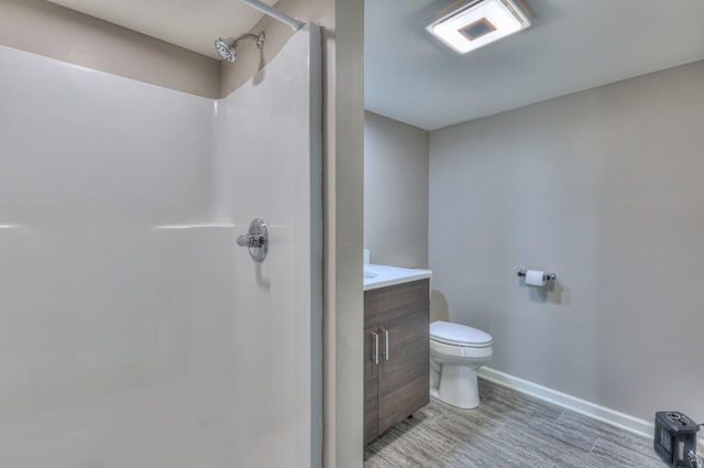 bathroom with a stall shower, vanity, toilet, and wood finished floors