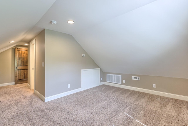 bonus room featuring light carpet, visible vents, and vaulted ceiling