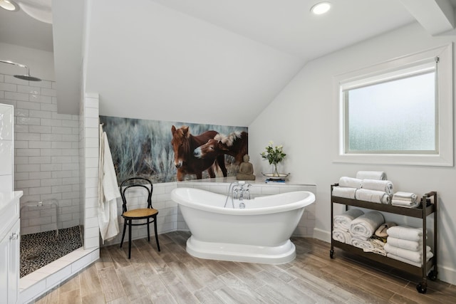 full bathroom with a walk in shower, lofted ceiling, wood finished floors, and a freestanding tub
