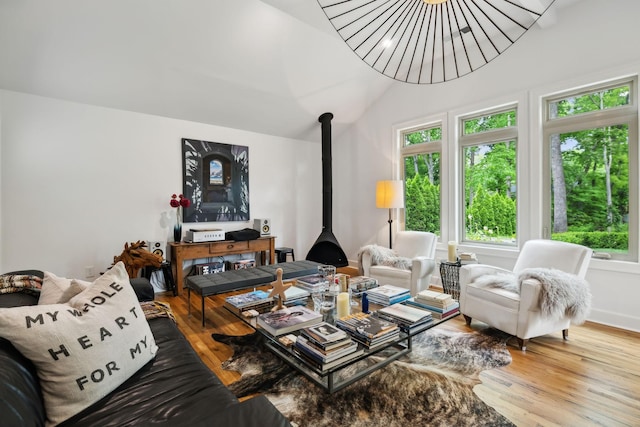 living area featuring a wood stove, wood finished floors, and lofted ceiling