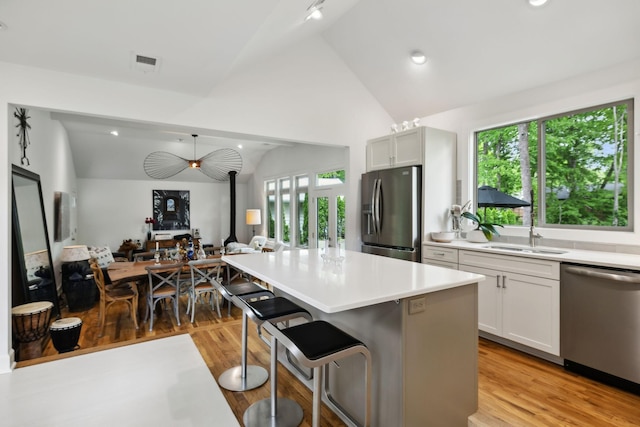 kitchen with stainless steel appliances, lofted ceiling, visible vents, and a sink