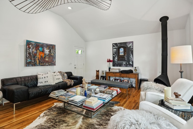living area with a wood stove, wood finished floors, and lofted ceiling