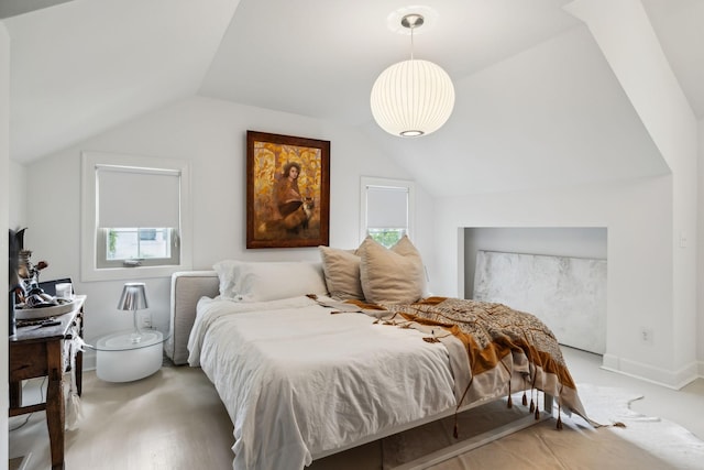 bedroom featuring light wood-style floors, lofted ceiling, and multiple windows