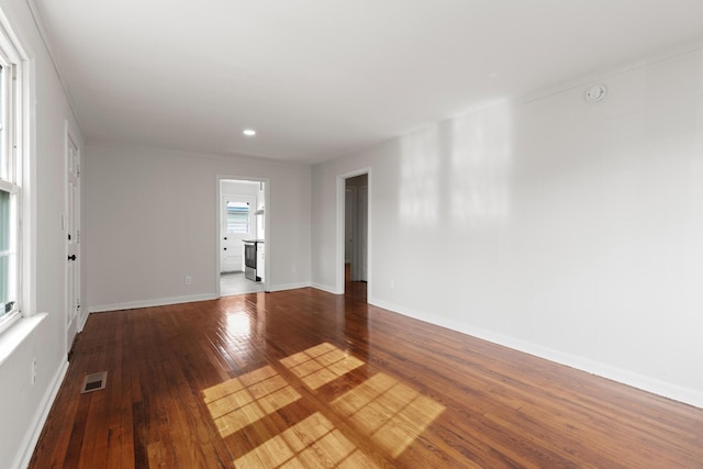 empty room featuring hardwood / wood-style flooring, baseboards, and visible vents