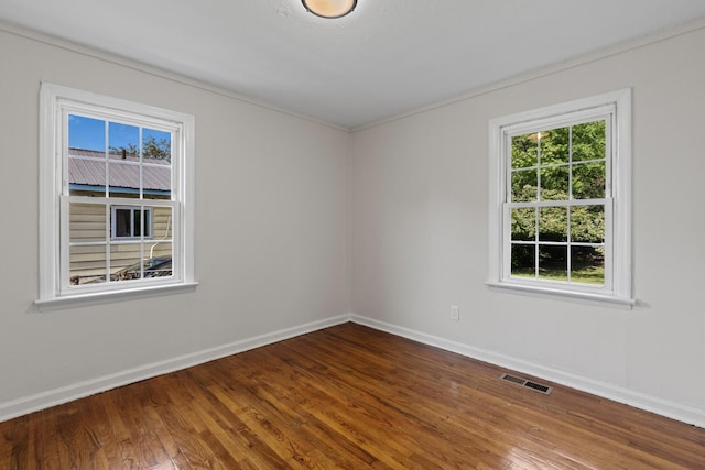 spare room featuring baseboards, visible vents, and wood finished floors