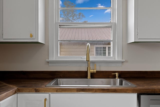 interior details featuring white cabinetry, dark countertops, and a sink
