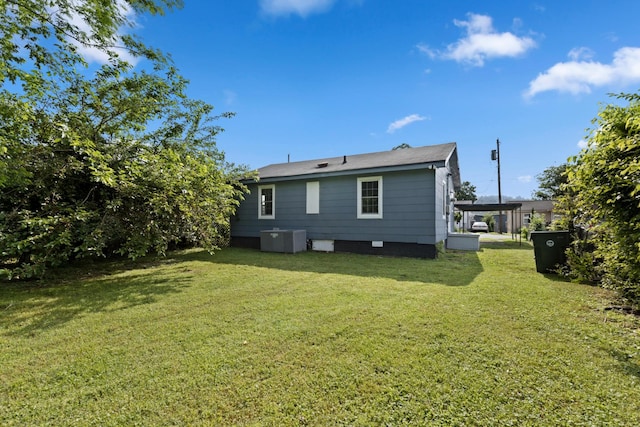 rear view of property featuring a lawn and central AC unit