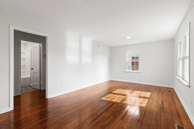 empty room featuring baseboards, wood-type flooring, and visible vents