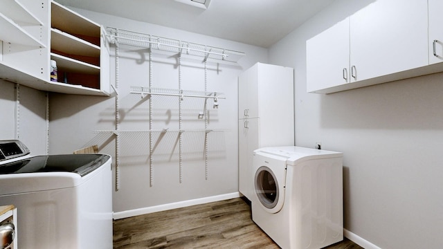 laundry area featuring cabinet space, baseboards, independent washer and dryer, and wood finished floors