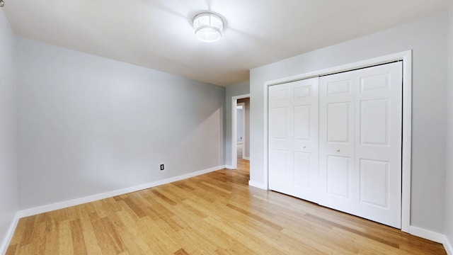 unfurnished bedroom with light wood finished floors, baseboards, and a closet