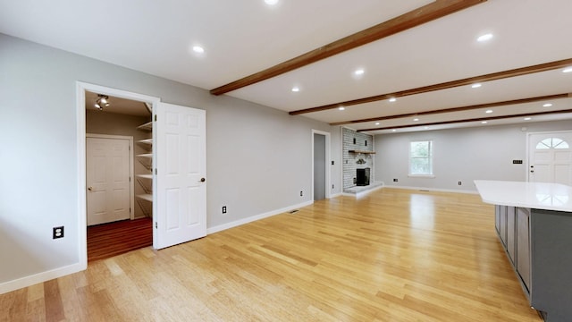unfurnished living room with light wood finished floors, beamed ceiling, baseboards, and recessed lighting