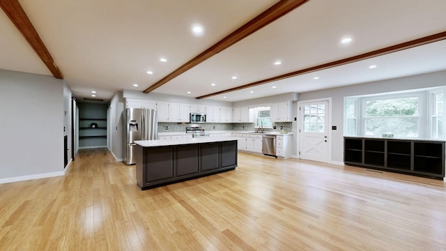kitchen with light countertops, beamed ceiling, white cabinets, and appliances with stainless steel finishes