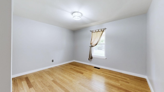 spare room featuring baseboards, visible vents, and wood finished floors