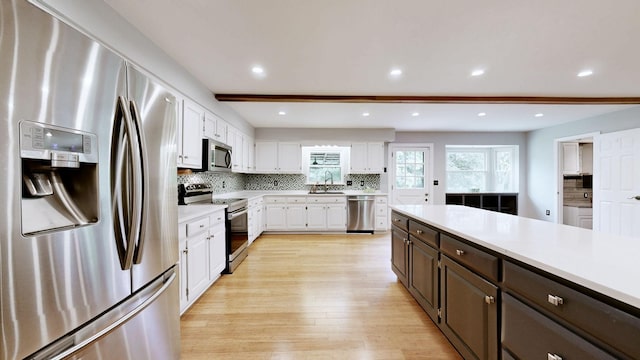 kitchen with a sink, light countertops, white cabinets, and appliances with stainless steel finishes