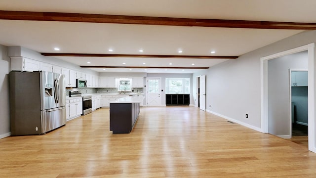 kitchen featuring light wood-type flooring, stainless steel appliances, white cabinets, and beam ceiling