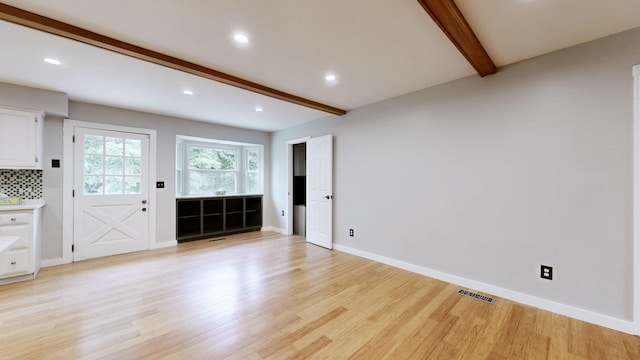 unfurnished living room with light wood-style flooring, visible vents, baseboards, beamed ceiling, and recessed lighting