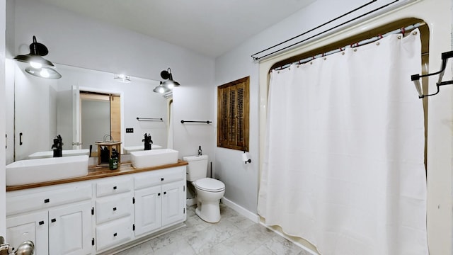 bathroom featuring double vanity, toilet, marble finish floor, and a sink