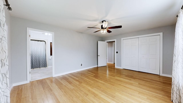 unfurnished bedroom featuring ensuite bathroom, light wood-style flooring, baseboards, and a closet