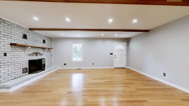 unfurnished living room featuring recessed lighting, beam ceiling, a fireplace, and light wood-type flooring