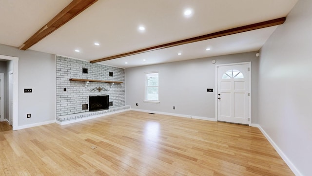 unfurnished living room featuring recessed lighting, a brick fireplace, light wood-type flooring, and beam ceiling