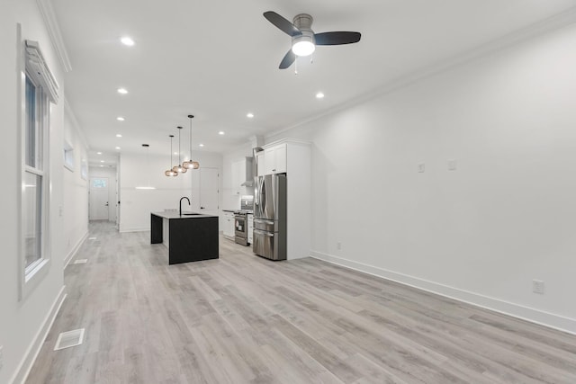 kitchen with a sink, stainless steel appliances, ornamental molding, visible vents, and a center island with sink