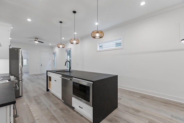 kitchen with a sink, recessed lighting, an island with sink, dark countertops, and appliances with stainless steel finishes