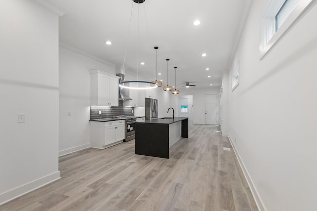 kitchen with appliances with stainless steel finishes, a sink, dark countertops, tasteful backsplash, and an island with sink